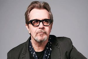 Gary Oldman wearing tinted thick-framed glasses