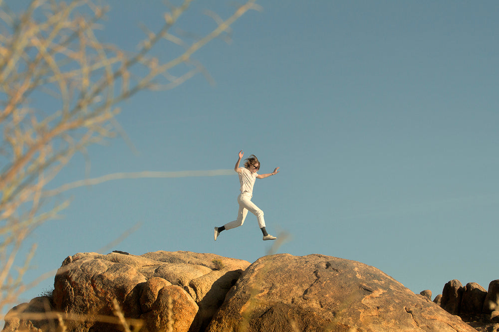 Photo of person jumping over rocks.